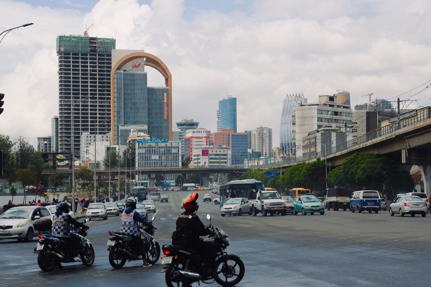 Boda-boda riders on a Nairobi highway beneath the city skyline