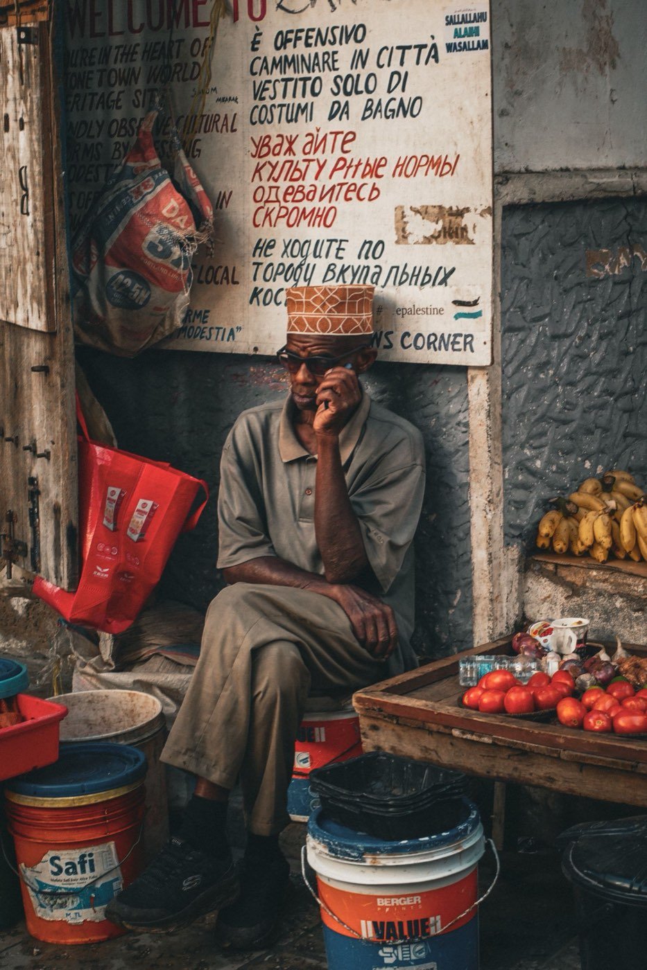 Shopkeeper seated among produce at a roadside stall